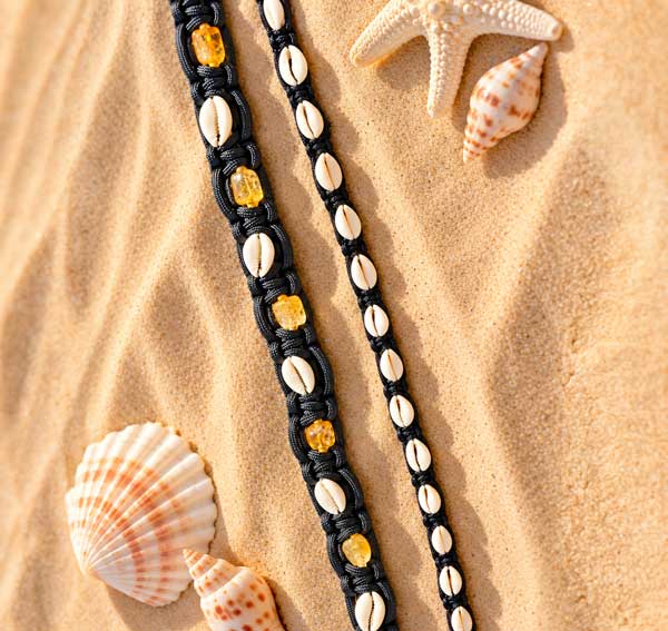 The Cowrie & Citrine collar shown with a half-inch small shell Classic Cowrie collar on the sand