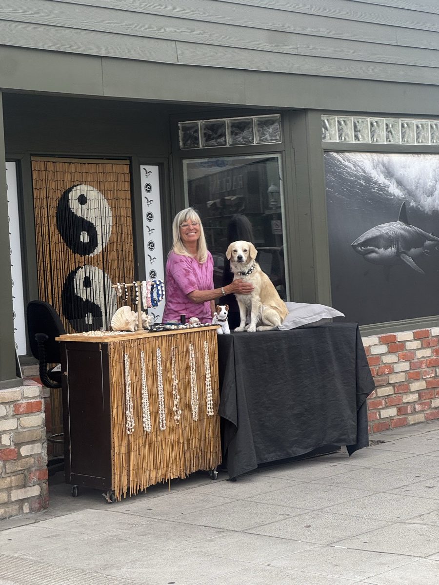 SurfPup founder with a dog at the collar table outside the shop
